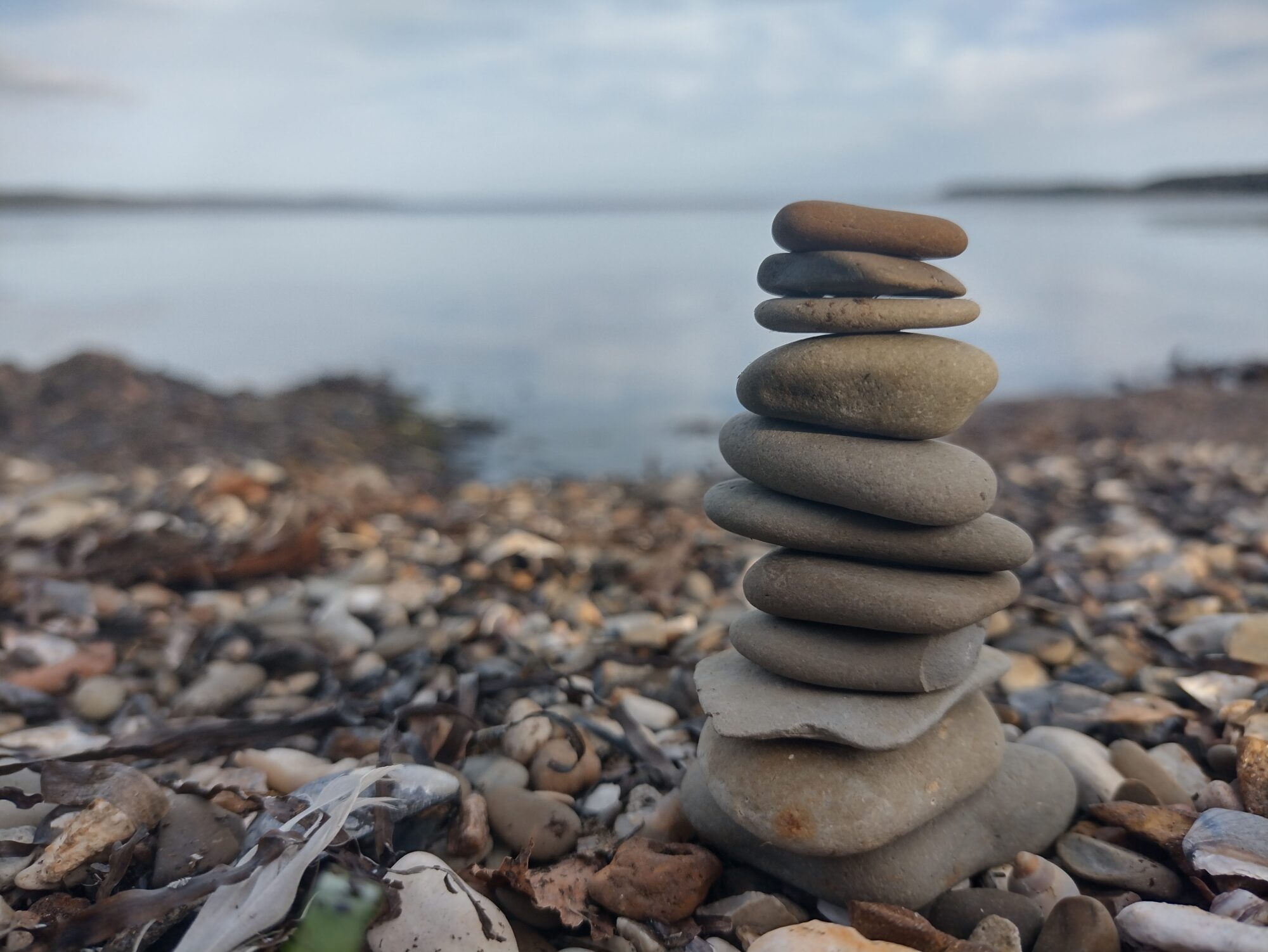 Sten stablet i balance ved vandet. Symboliserer ro, nærvær og indre balance med naturterapi, retreats og teambuilding.